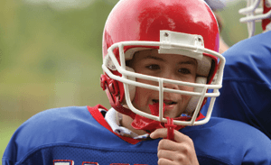 Dog Wearing Football Helmet And Jersey Chewing On Football High